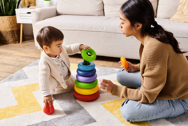 Молода азіатська мати щасливо взаємодіє зі своїм маленьким сином на підлозі їх затишної вітальні, створюючи веселі спогади разом. - Фото, зображення