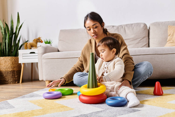 Una giovane madre asiatica gioca gioiosamente con il suo piccolo figlio sul pavimento del loro soggiorno. - Foto, immagini