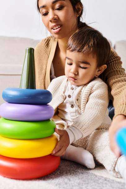 Una giovane madre asiatica e il suo piccolo figlio giocano felicemente con una pila di giocattoli in salotto. - Foto, immagini