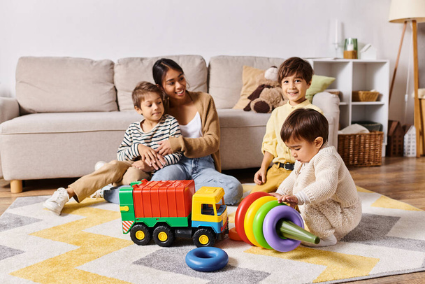 Een jonge Aziatische moeder en haar zoons spelen gelukkig met speelgoed in hun woonkamer. - Foto, afbeelding