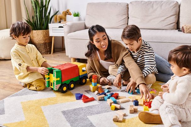 Un gruppo di bambini, guidati dalla loro madre asiatica, immersi in attività ludiche con vari giocattoli sul pavimento del soggiorno. - Foto, immagini