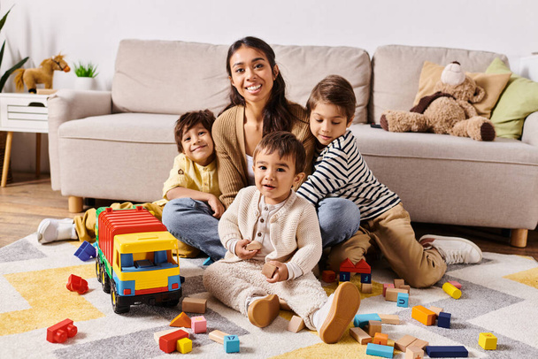 Eine junge asiatische Mutter sitzt mit ihren kleinen Söhnen im gemütlichen Wohnzimmer auf dem Fußboden. - Foto, Bild
