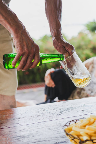Χέρι ανθρώπου ρίχνει μπύρα από ένα μπουκάλι σε ένα ποτήρι - Φωτογραφία, εικόνα