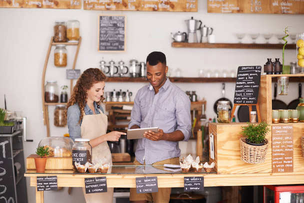 Συνεργασία, κατάστημα μικρών επιχειρήσεων και tablet με ιδιοκτήτη σε καφετέρια μαζί για σχεδιασμό ή εξυπηρέτηση. Ομαδικότητα, τεχνολογία για ηλεκτρονικό εμπόριο ή online παραγγελία με άντρα και γυναίκα σε cafe ή εστιατόριο. - Φωτογραφία, εικόνα