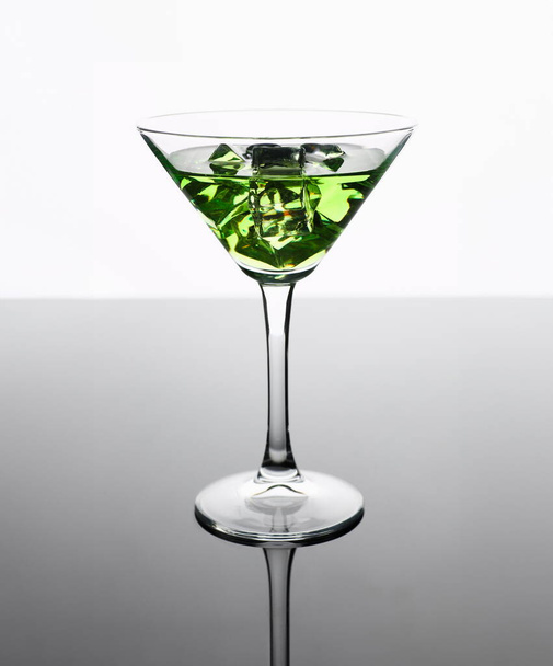 Cóctel de absenta con vodka en martini impresión de vidrio para cocina con piel fondo interior bar productos muebles para el hogar diseño de moda negro gradiente gris en rodajas frutas y hielo
. - Foto, Imagen