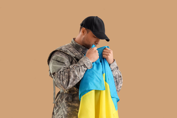 Soldado masculino com bandeira ucraniana em fundo marrom - Foto, Imagem