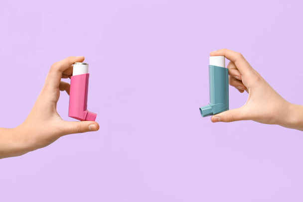 Manos de niño con inhaladores de asma sobre fondo lila - Foto, imagen