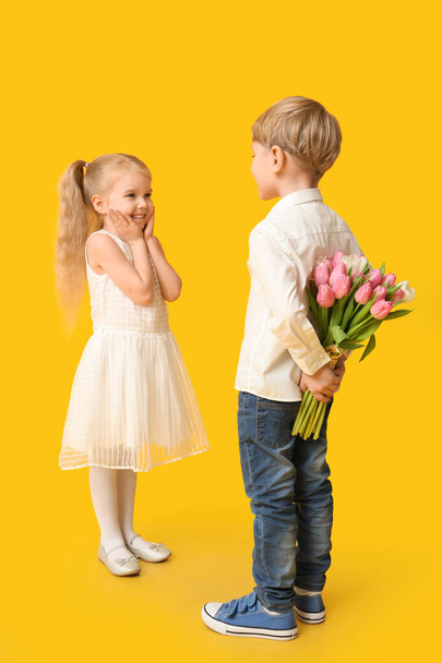 Söpöjä lapsia, joilla on kimppu kauniita tulppaaneja keltaisella taustalla. Kansainvälinen naistenpäivä - Valokuva, kuva