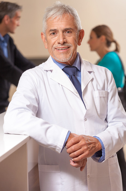 Confident smiling mature male doctor in hospital waiting room - Fotó, kép