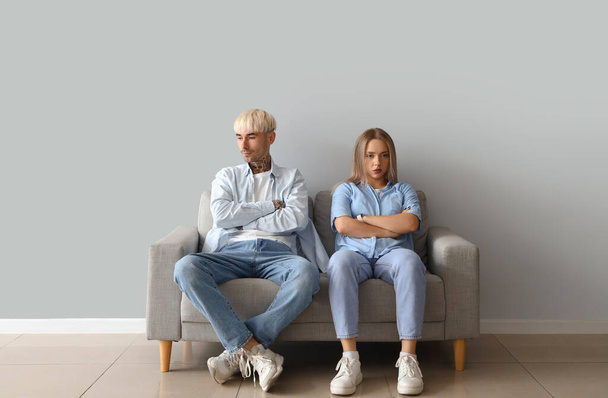 Молода пара сидить на дивані біля світлої стіни - Фото, зображення