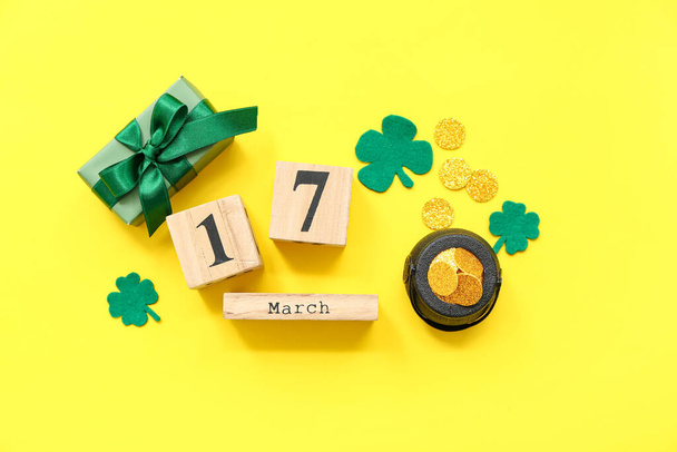 Potje met gouden munten, geschenkdoos en kalender op gele achtergrond. St. Patrick 's Day viering - Foto, afbeelding