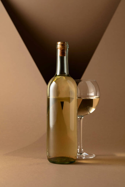 Bottle and glass of white wine on a beige background. Copy space. - Foto, Imagem