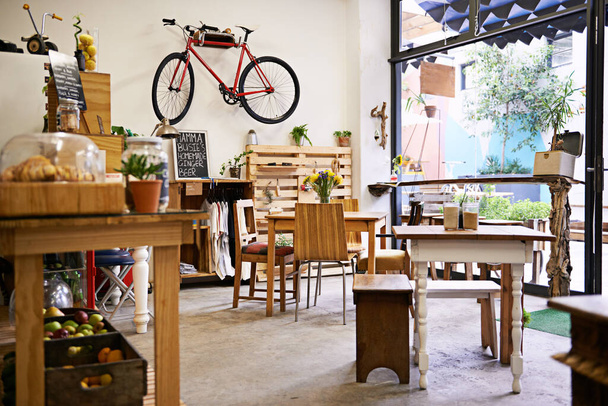Εσωτερικό, ποδήλατο στον τοίχο του άδειου καφενείου με τραπέζια και καρέκλες για λιανική πώληση, εξυπηρέτηση ή φιλοξενία. Χώρος, μικρή επιχείρηση ή startup εστιατόριο με καφετέρια καθίσματα για bistro consumerism. - Φωτογραφία, εικόνα