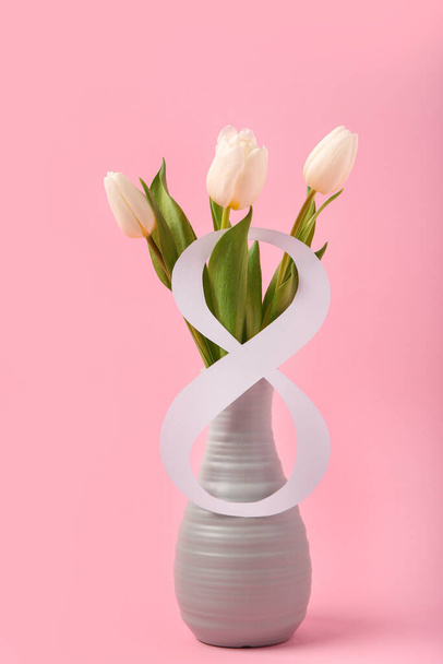 Vase mit schönen weißen Tulpen und Figur 8 aus Papier auf rosa Hintergrund. Internationaler Frauentag - Foto, Bild