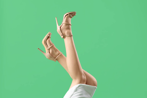 Nohy mladé ženy ve stylové béžové vysoké podpatky na zeleném pozadí - Fotografie, Obrázek