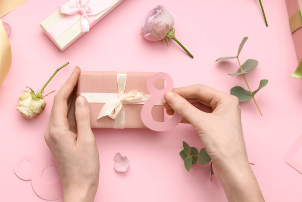 Manos femeninas con cajas de regalo y hermosas rosas sobre fondo rosa. Día Internacional de la Mujer - Foto, Imagen