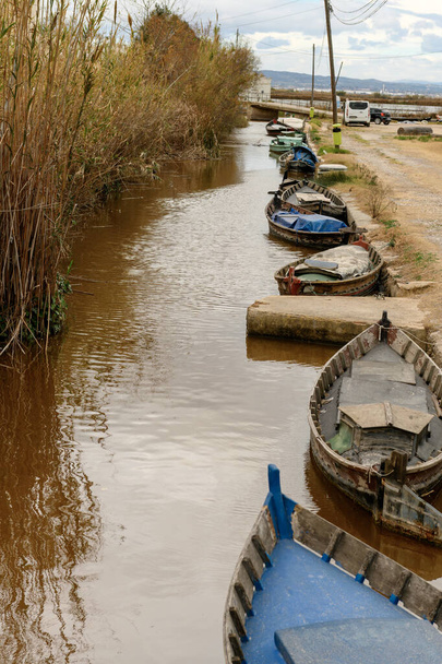 Tradiční dřevěné čluny kotvící podél kanálu, s rustikálním šarmem města Albufera Valencie lemující břehy - Fotografie, Obrázek