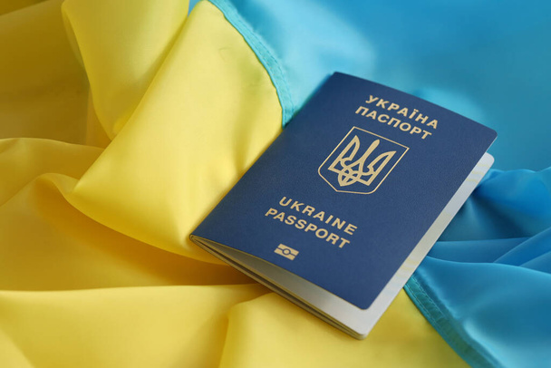 One Ukrainian biometrical passport on folded waving flag of Ukraine country close up - Photo, Image
