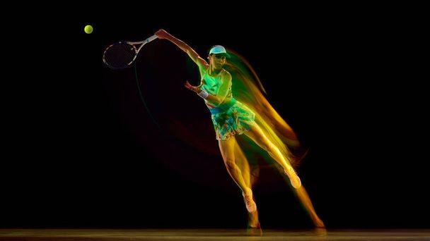 Desportista em quadra de tênis com redemoinho de cores destacando movimento contra fundo de estúdio preto. Conceito de esporte, estilos de vida ativos, torneios e eventos, energia, movimento. - Foto, Imagem