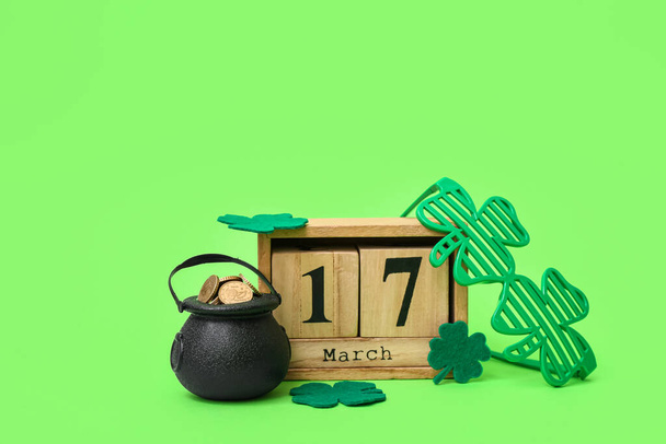 Pot avec pièces d'or, calendrier et lunettes en plastique sur fond vert. Célébration de la Saint Patrick - Photo, image