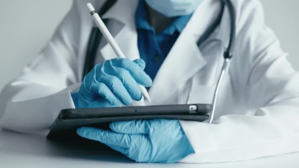 Online-Gesundheit: Eine Ärztin schreibt aktiv auf einem Touch-Tablet und analysiert medizinische Indikatoren. Medizintechnik in Aktion: Der Arzt gibt die Daten sorgfältig auf dem Touch-Tablet ein und sorgt so für - Filmmaterial, Video