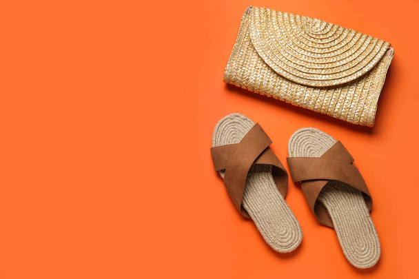 Stylish brown sandals and wicker bag on orange background - Photo, Image