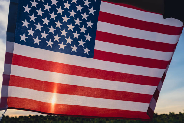 Heiluttaa Amerikan lippua auringon taustalla. Amerikan yhdysvaltojen lippu. Itsenäisyyspäivän muistopäivä. USA:n isänmaallisuus Kansallispäivä. Vaalipäivä, Usa ylpeä. Muista ja kunnioita. Työvoima - Valokuva, kuva