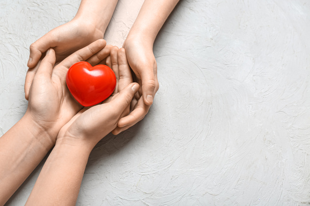 Ruce ženy a dítěte drží červené srdce na bílém pozadí - Fotografie, Obrázek