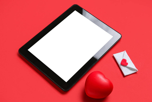 Tafelcomputer met liefdesbrief en hart op rode achtergrond. Concept van online dating - Foto, afbeelding