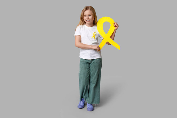 Έφηβη με κίτρινη κορδέλα σε γκρι φόντο. Διεθνής Ημέρα κατά του καρκίνου της παιδικής ηλικίας - Φωτογραφία, εικόνα