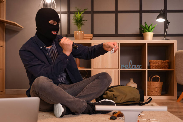 Άνδρας κλέφτης με φακό κλέβει κοσμήματα στο δωμάτιο τη νύχτα - Φωτογραφία, εικόνα