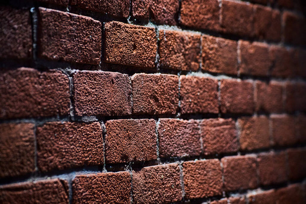 Gros plan du mur de briques rustiques du centre-ville d'Ann Arbor, Michigan, mettant en évidence les tons terreux et la texture graveleuse sous l'éclairage nocturne - Photo, image