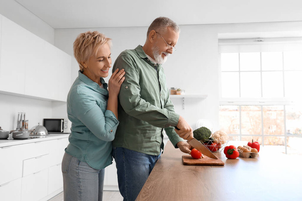 Couple d'âge mûr couper la tomate dans la cuisine - Photo, image