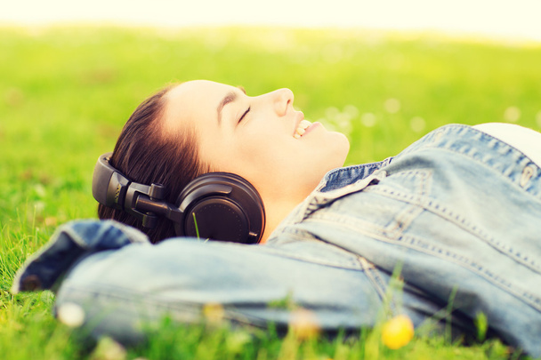 smiling young girl in headphones lying on grass - Photo, Image