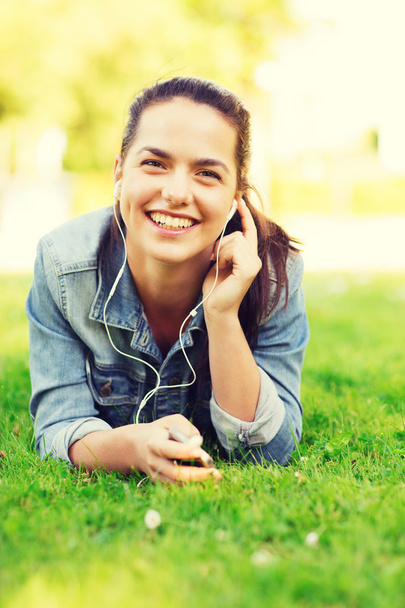 smiling young girl with smartphone and earphones - 写真・画像