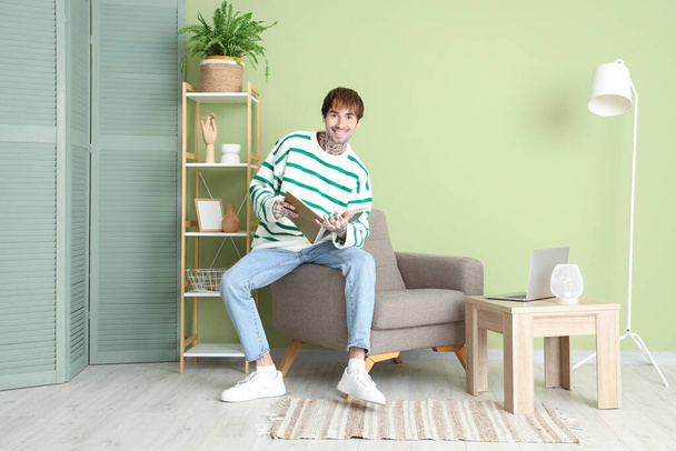 Schöner Mann liest Magazin auf weichem Sessel zu Hause - Foto, Bild