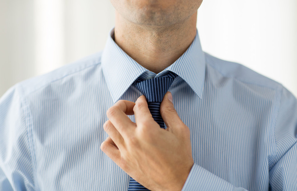 close up of man in shirt adjusting tie on neck - Fotografie, Obrázek