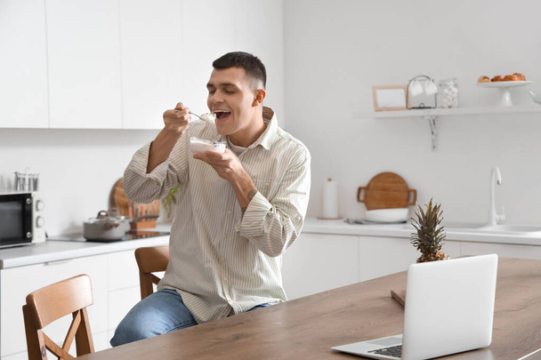 Junger Mann isst leckeren Joghurt in Küche - Foto, Bild