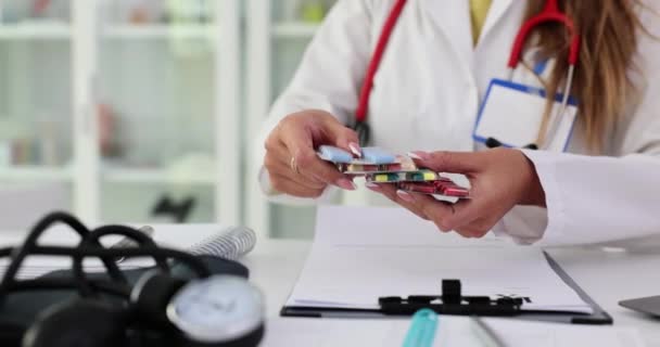 Γυναίκα γιατρός κατέχει τη συσκευασία των διαφόρων blisters χάπι στα χέρια σε closeup χώρο εργασίας. Ορμονικά ηρεμιστικά - Πλάνα, βίντεο