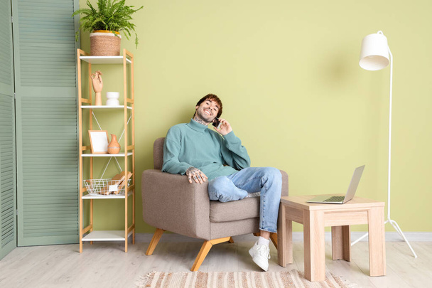 Hombre guapo hablando por teléfono móvil en sillón suave en casa - Foto, Imagen