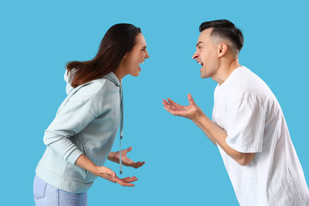 Angry young couple quarreling on blue background - Photo, Image