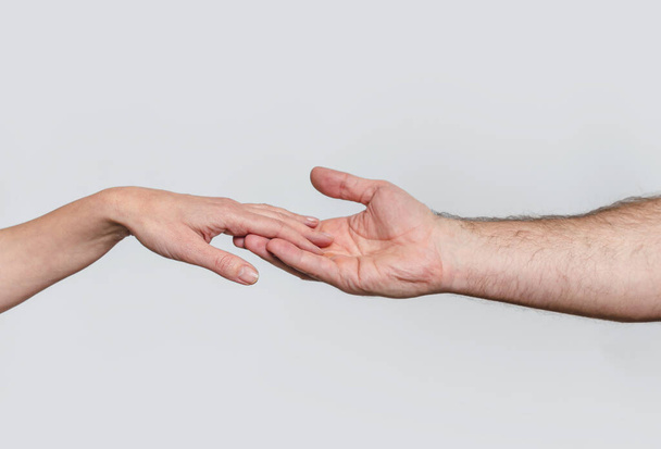 男性の手は女性の手を丁寧に支えています. グレーの背景。 調和した関係のシンボル - 写真・画像