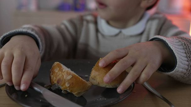 Ustaca atıştırmalık ekmeği dilimler, karbonhidrat hazırlar ve karbonhidrat açısından zengin yiyeceklerden bir ısırık alır. 5 yaşında çocuk atıştırması. - Fotoğraf, Görsel