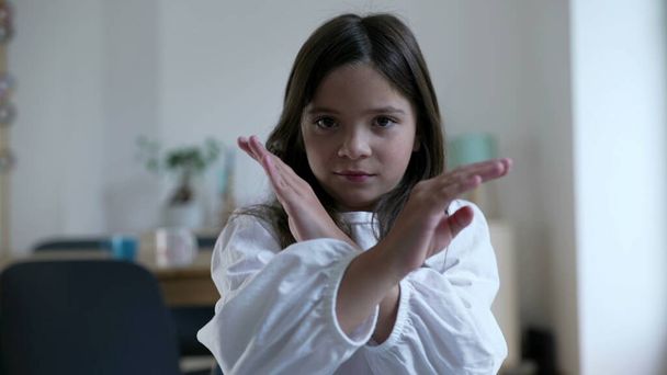 Kind gestikuliert NEIN mit in X-Form gekreuzten Armen und fuchtelt mit dem Finger in NEGATION und lehnt Angebot ab - Foto, Bild