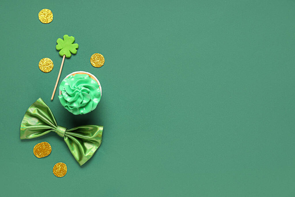 Tasty cupcake with bow tie and decor for St. Patrick's Day on green background - Photo, Image