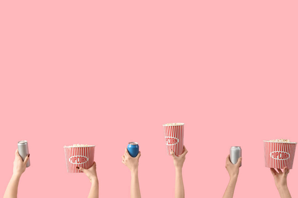 Hands holding buckets with popcorn and drinks on pink background - Photo, Image