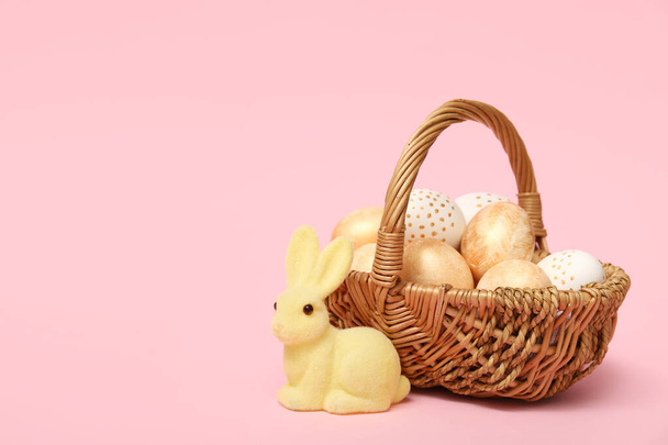 Košík s velikonočními vejci a králičí figurka na růžovém pozadí - Fotografie, Obrázek