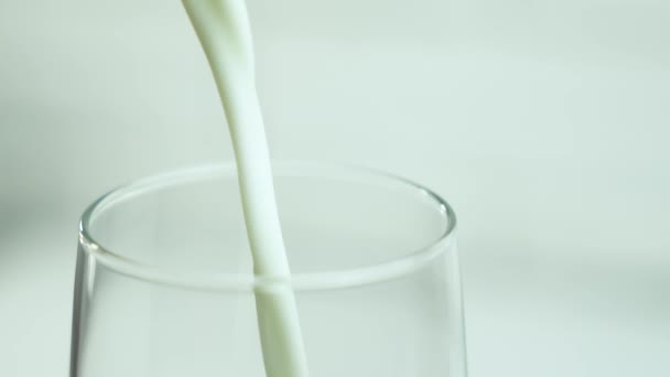 Kaada maitoa lasiin pullosta kevyellä neutraalilla pohjalla, jossa on tilaa tekstille, kopioi tilaa. - Materiaali, video
