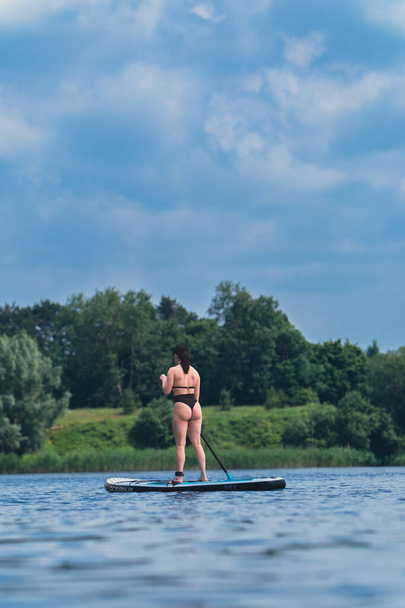 attractive woman in swimwear on supboard in the middle of the lake - Photo, Image