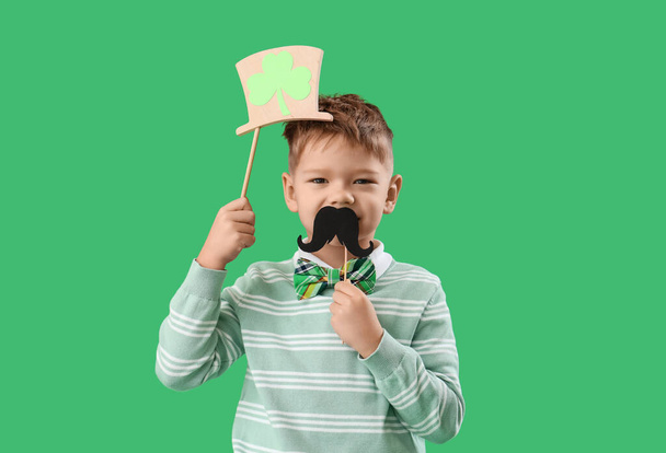 Lindo niño con sombrero de duende y bigote de papel sobre fondo verde. Celebración del Día de San Patricio - Foto, imagen